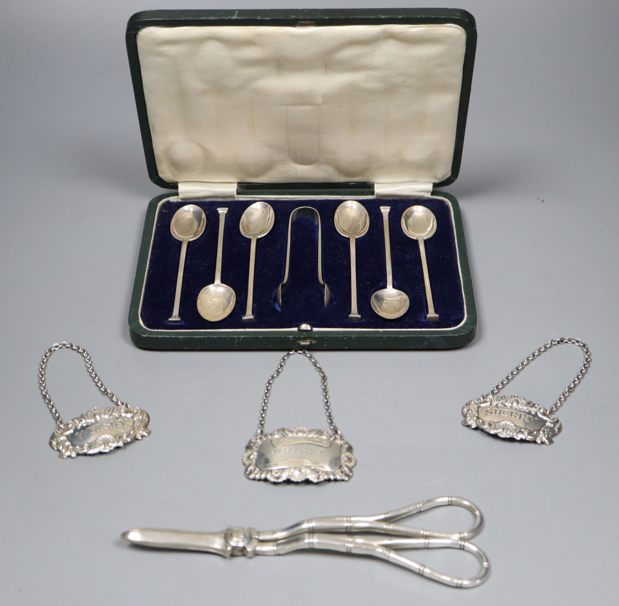 A collection of small silver to include a cased set of six coffee spoons and tongs, three wine labels and a pair of grape scissors